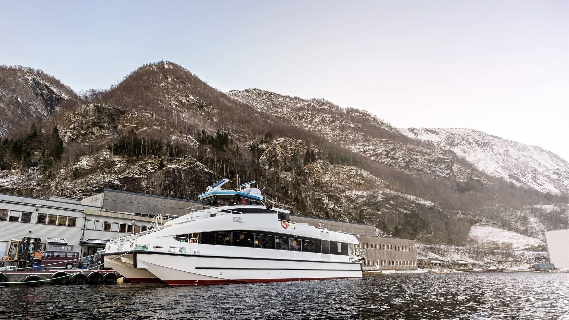 OBLUE FERRY 26 alongside the quay with snow-covered mountains behind