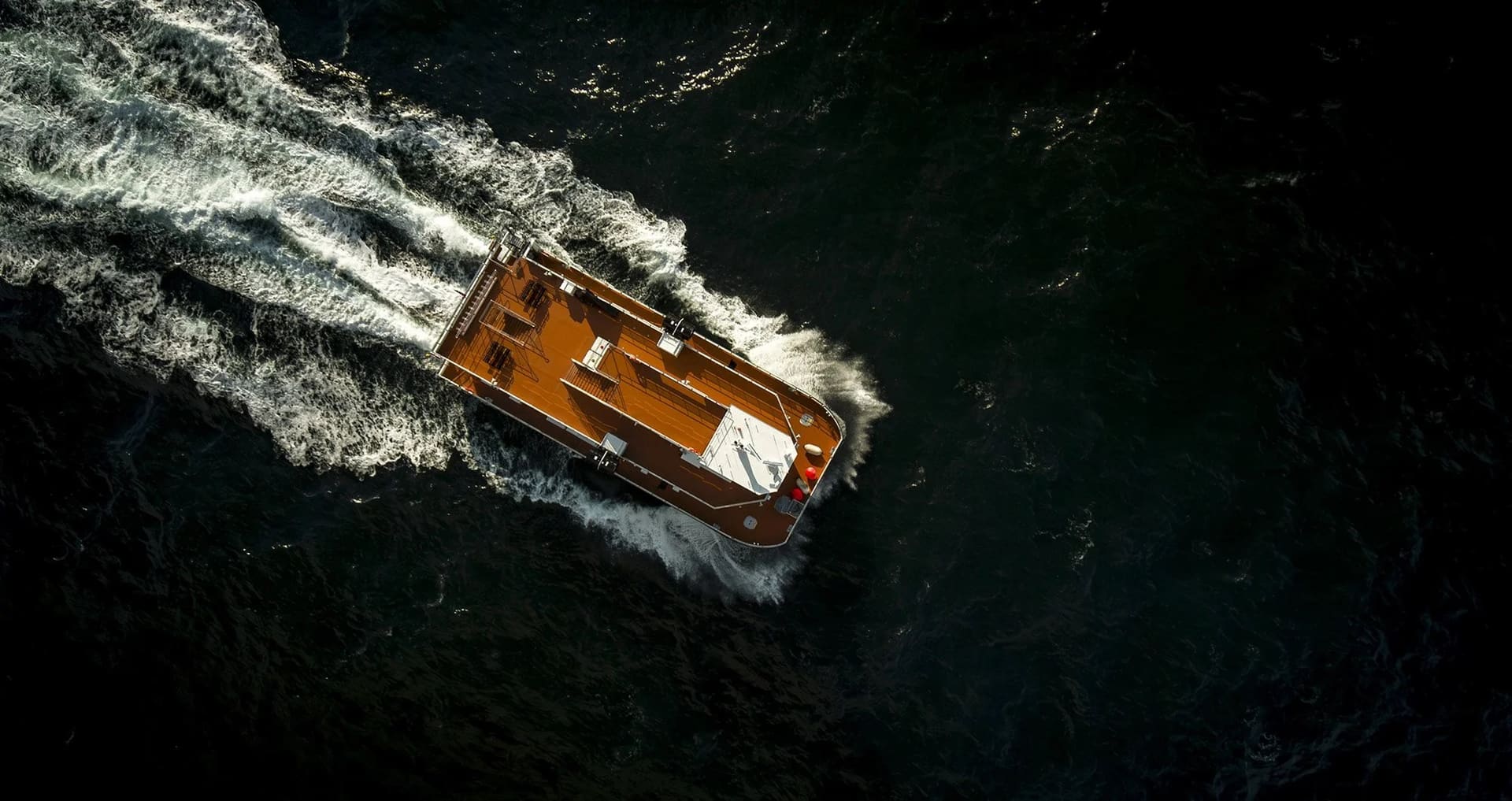 Top-down aerial view of the OBLUE FERRY 26H sundeck on dark water