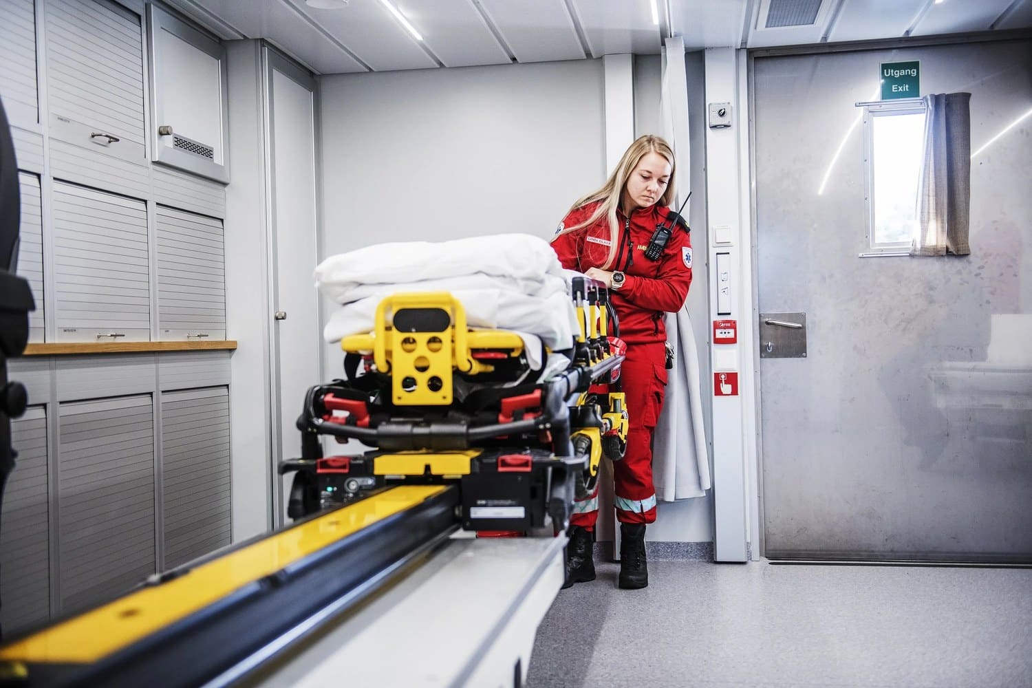 Paramedic handling a rolling stretcher inside the ambulance room